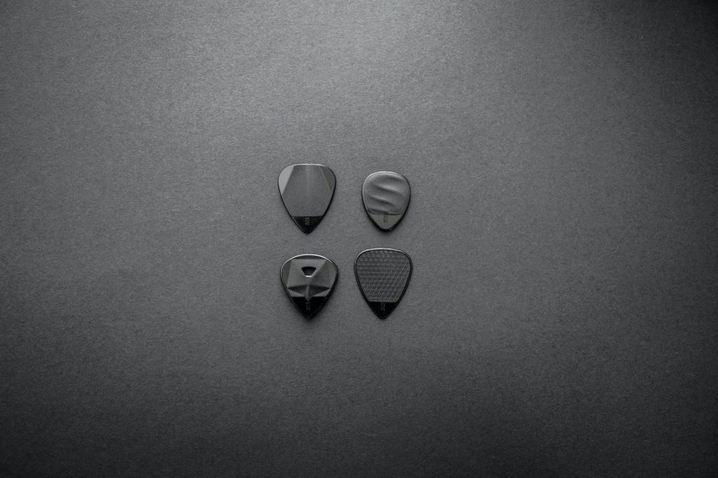 grayscale photography of four guitar picks