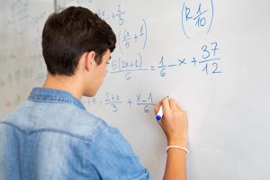 young student doing math on whiteboard