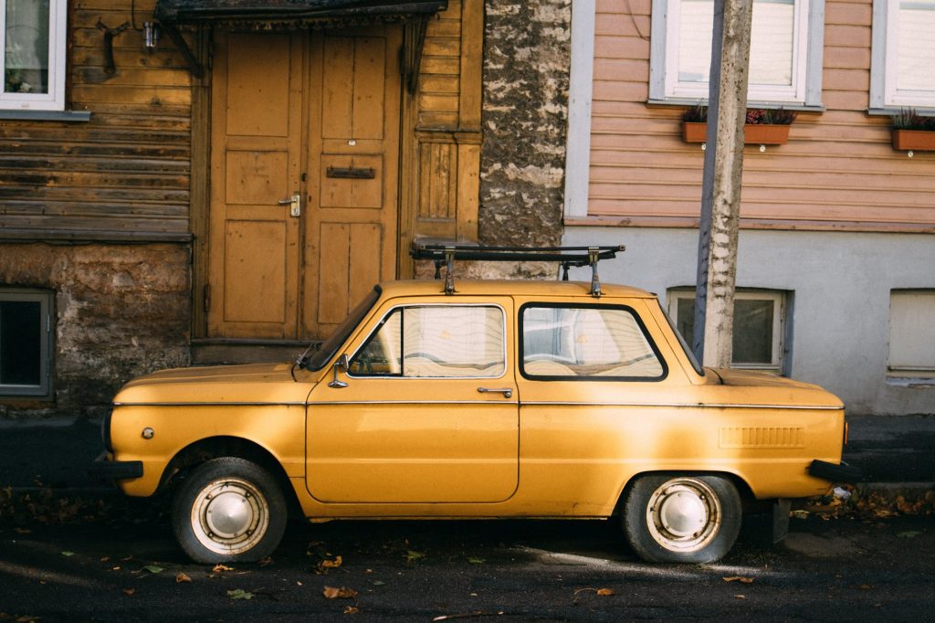 yellow retro car parked outside old building