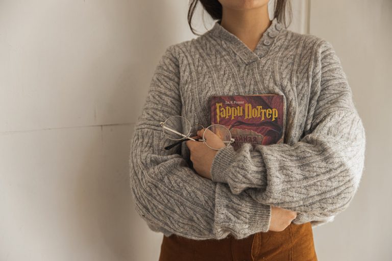 woman in gray sweater holding a book