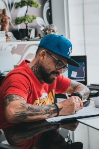 focused bearded man drawing tattoo sketches