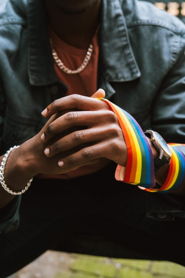 crop faceless black man with rainbow ribbon on hand