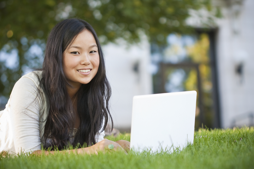 student with laptop on grass