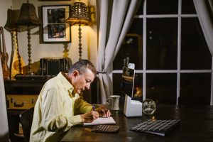 focused man taking notes in planner during remote work at home at night