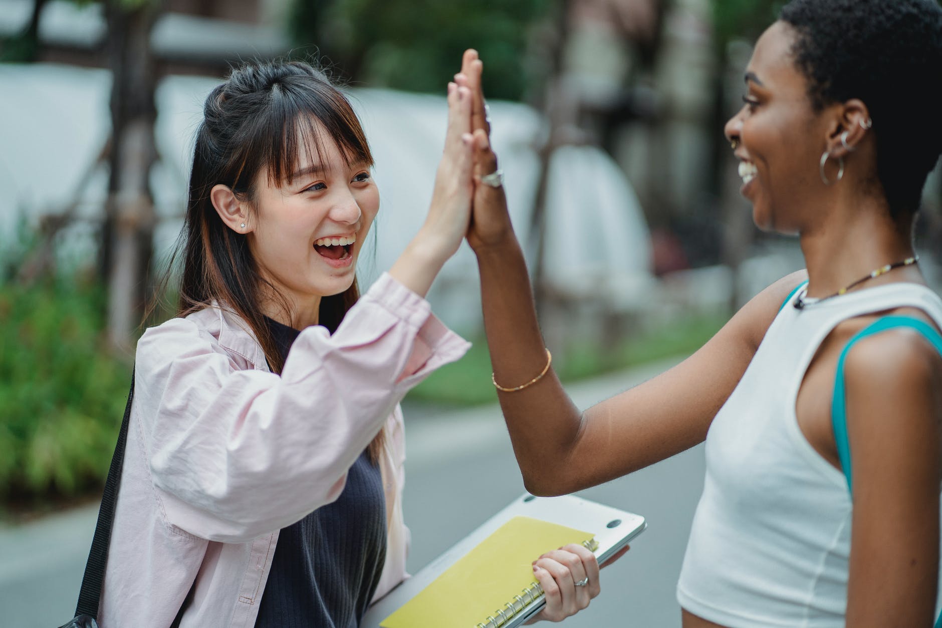 joyful diverse students giving high five in park