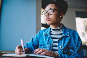 Female student thoughtful looking away and thinking about idea for an essay