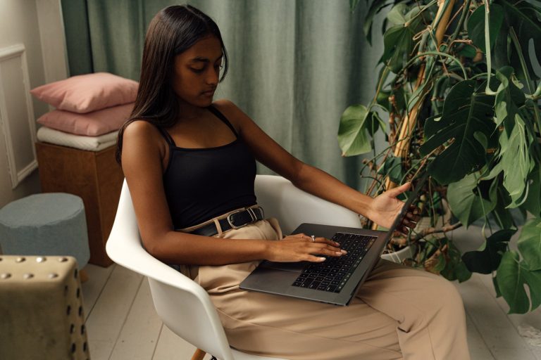 girl sitting on a chair while using her laptop