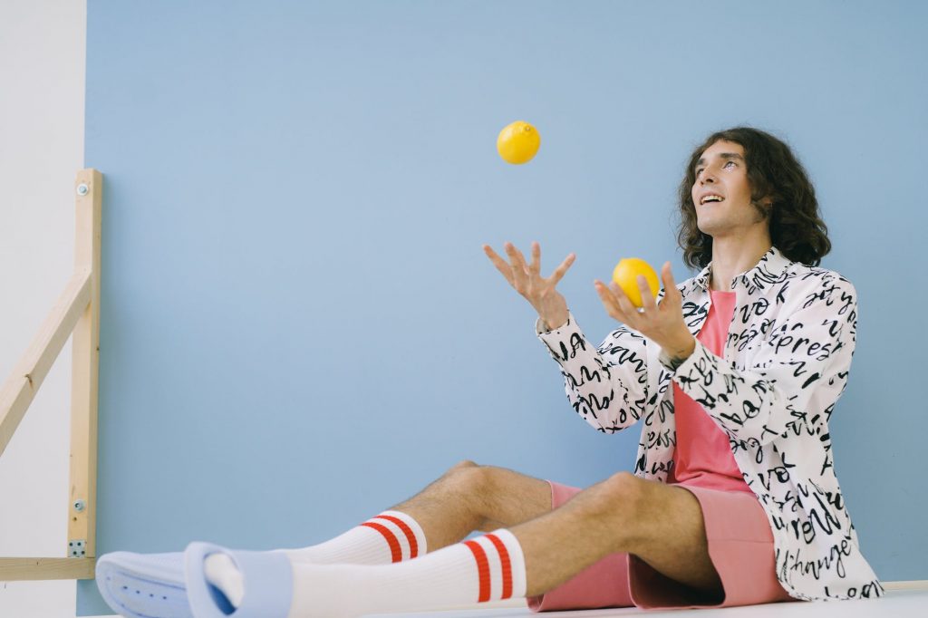 transsexual man sitting and juggling two yellow lemons