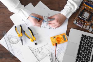 Male,Hands,Drawing,Electrical,Blueprint,At,Wooden,Table,,Top,View