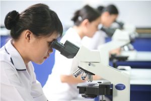 A group of female students in a lab looking at a microscope