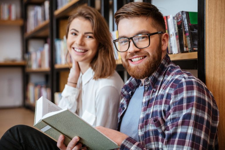 couple smiling and working together in library