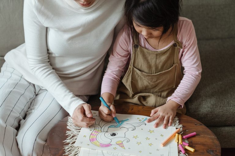 Parent sitting with child and coloring.