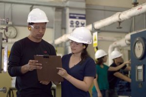 A male and female industrial engineers working together looking at a clipboard