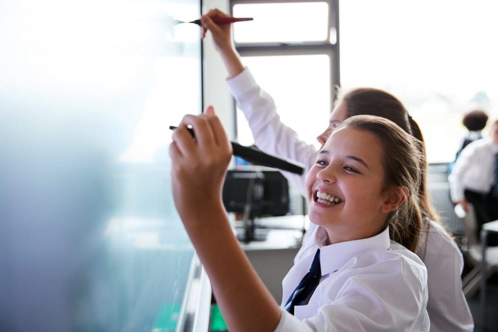 young students writing on chalkboard