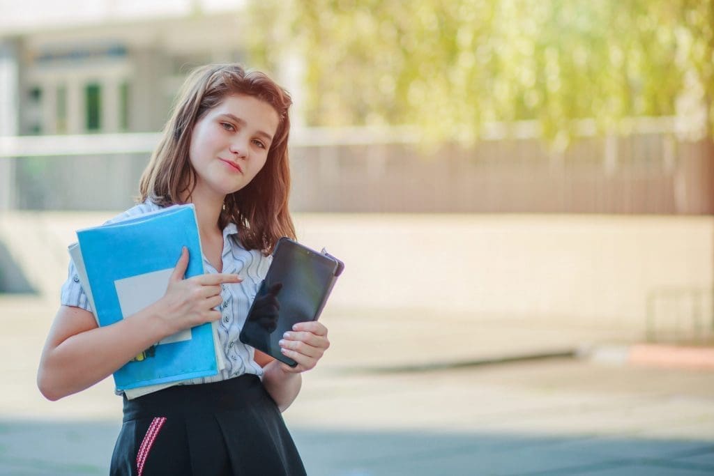 young girl holding tablet and textbooks