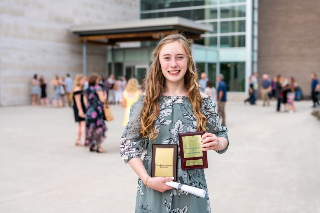 Middle school student holding eighth grade graduation award.