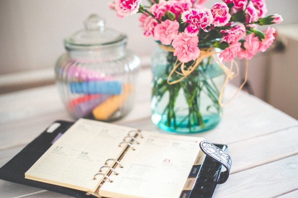 New Year's reset tips with a personal organizer and pink flowers on desk