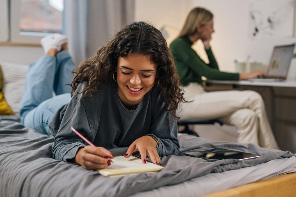 student doing homework on bed