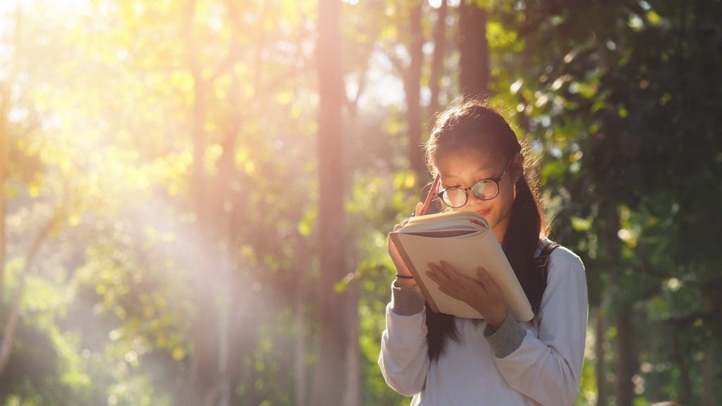 girl reading book in a park