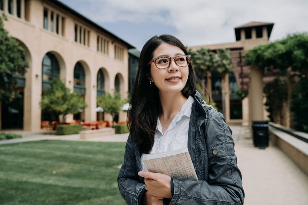 student holding a book on campus