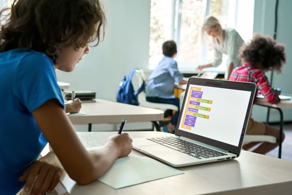 School student using laptop in class to schedule New Year's reset schedule.