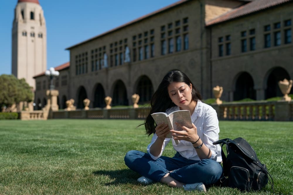 student reading a book on the grass