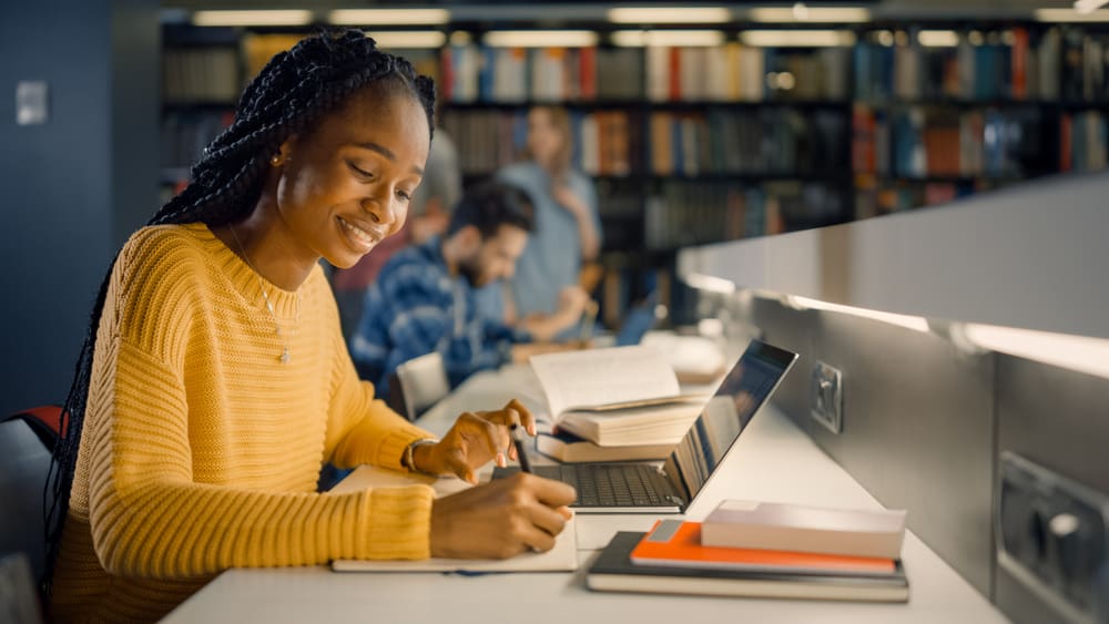 University,Library:,Gifted,Black,Girl,Uses,Laptop,,Writes,Notes,For