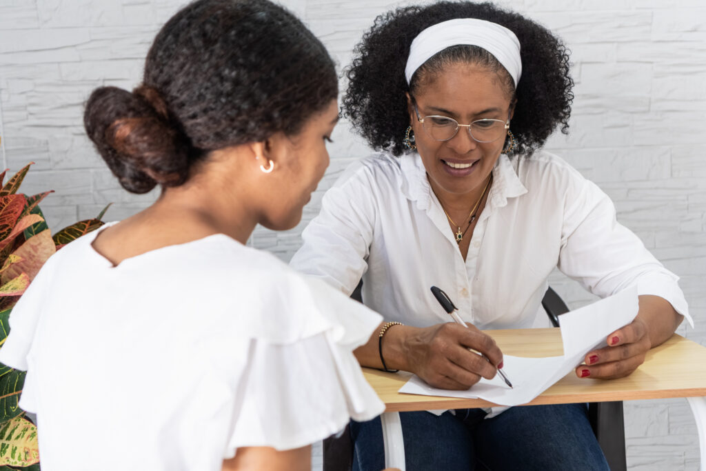 Mother and daughter smiling while signing university acceptance documents together
