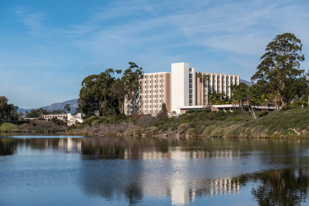 Goleta, CA, USA - January 2, 2020: UCSB, University California Santa Barbara. San Nicolas Residential Hall set at Campus Lagoon and partly surrounded by green trees and vegetation. Blue sky.