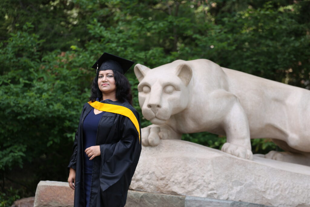 Graduate student at Penn State campus with Nittany Lion statue
